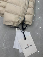 Close-up of beige quilted puffer coat sleeve cuff with Moncler patch and tags