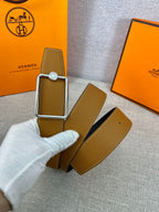 Tan leather belt with silver-tone buckle frame and round logo plate