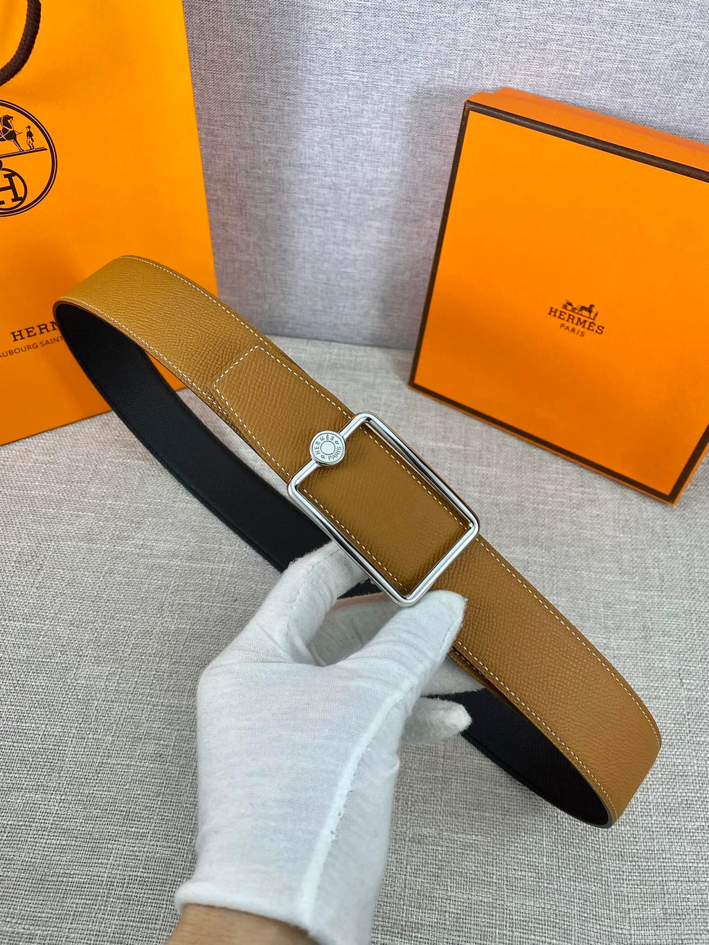 Tan leather belt with gold-tone square buckle and round logo plate