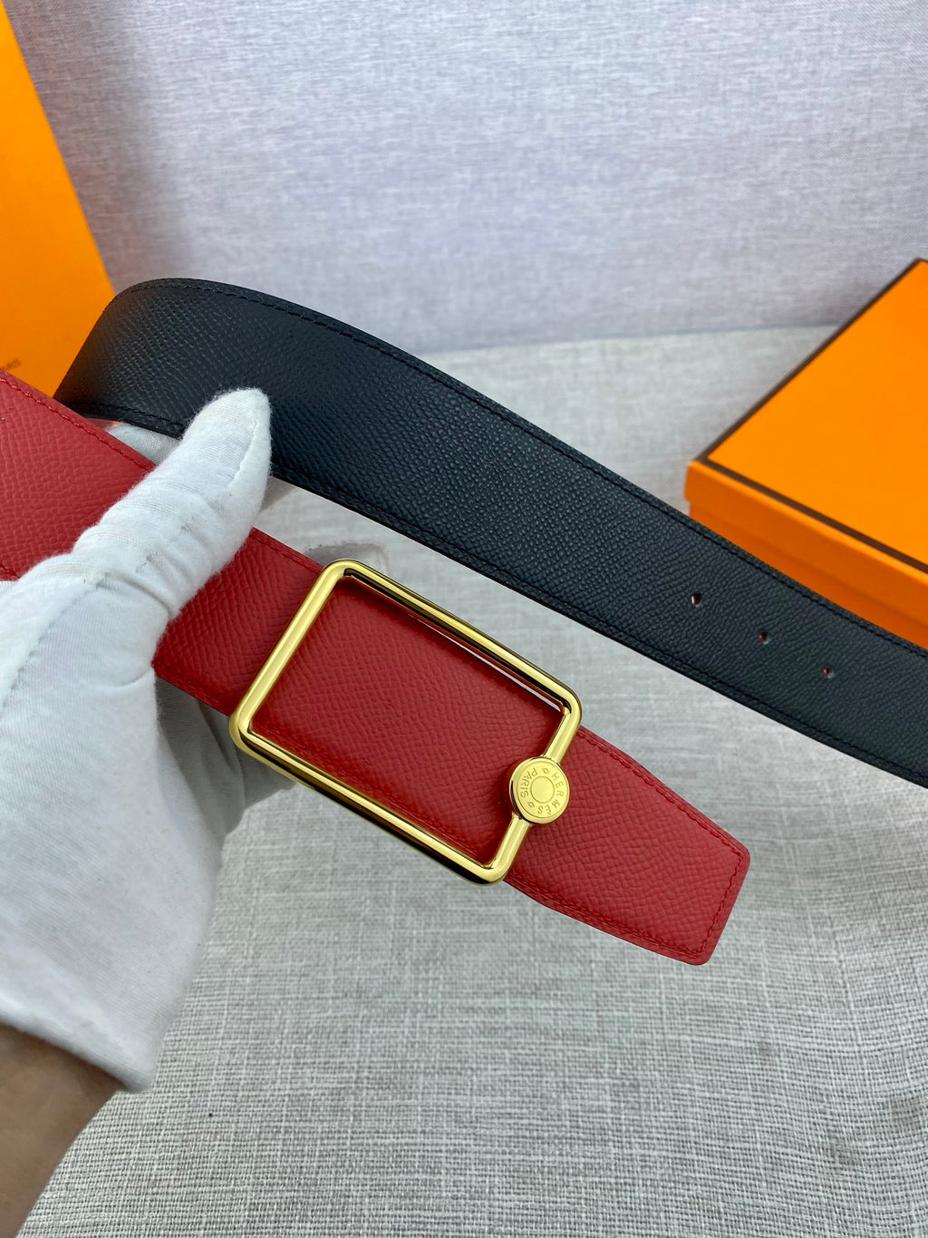 Hermes belt red strap with gold buckle, paired with dark navy backing
