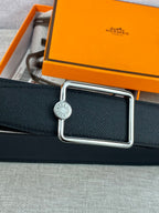 Navy leather belt close-up with silver rectangular buckle and circular emblem