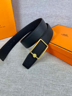 Navy leather belt laid flat with gold rectangular buckle and round emblem