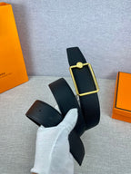 Navy leather belt detail with gold rectangular buckle and round engraved charm