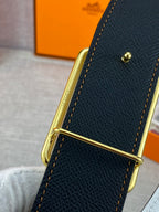 Dark textured leather belt close-up with gold buckle and stitching detail.
