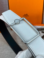 Light blue leather belt close-up with silver buckle and round branded medallion.