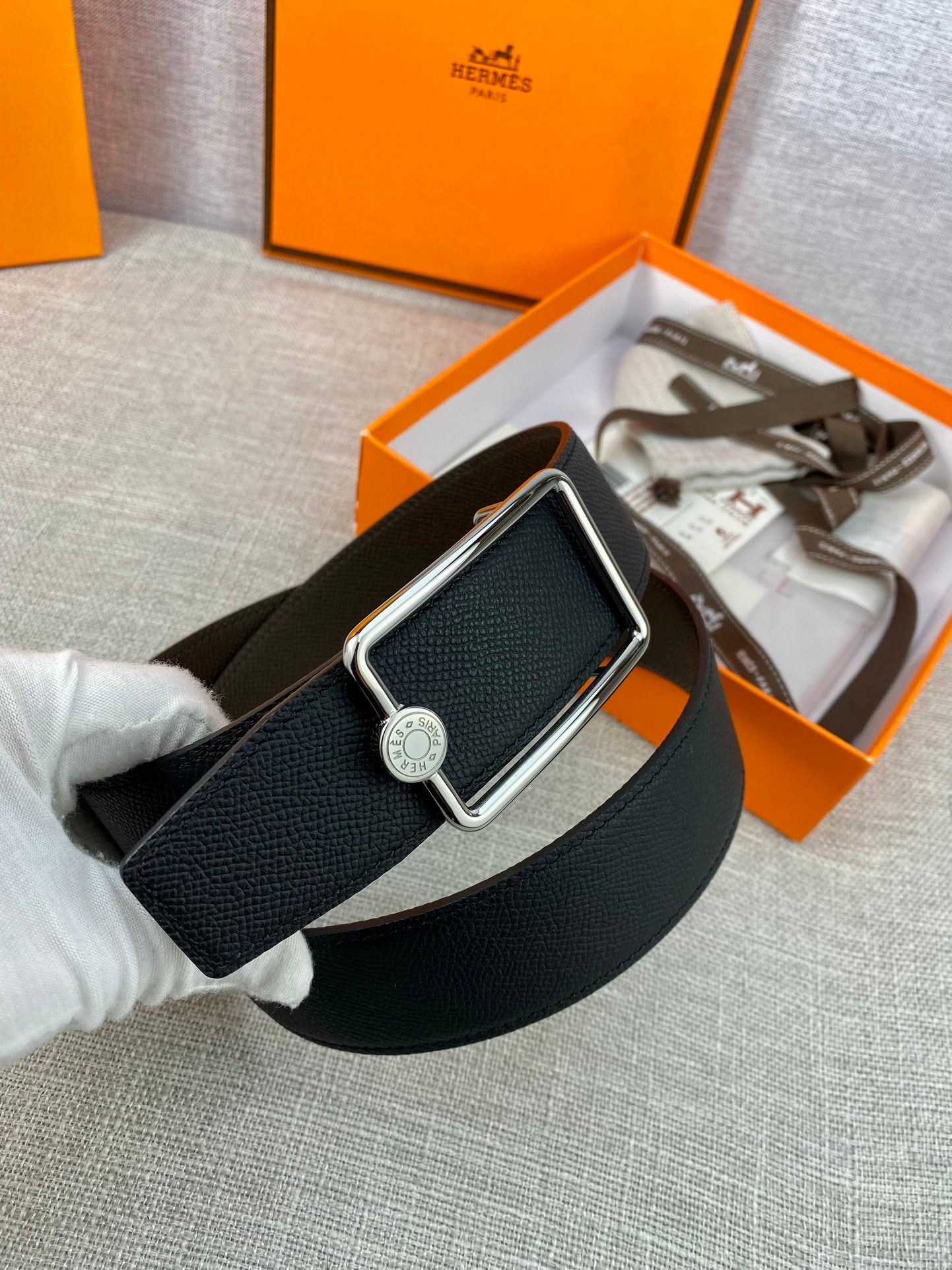 Hermes belt in dark leather with silver rectangular buckle and round logo