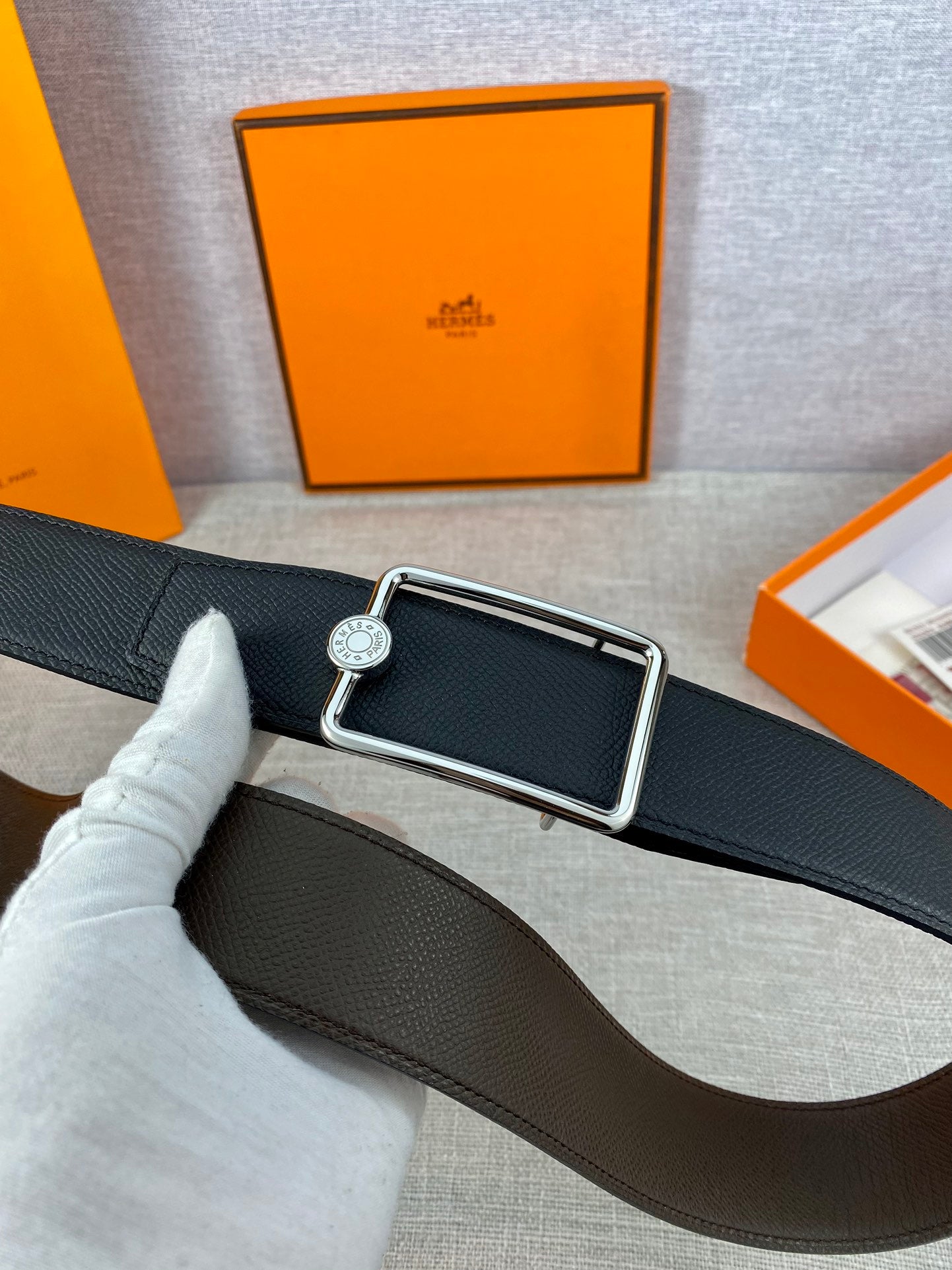 Hermes belt in dark leather with silver rectangular buckle and round logo