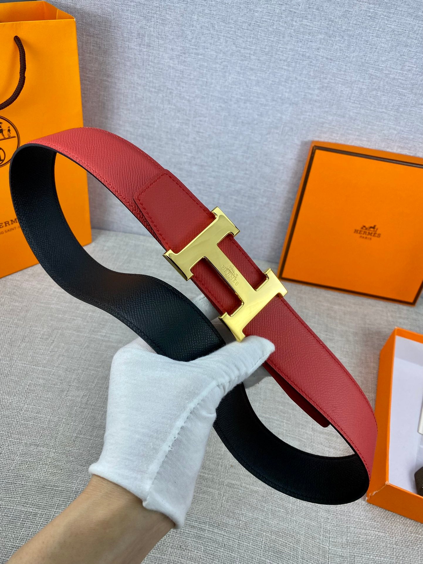 Hermes belt with red leather strap and gold-tone H buckle, black underside shown