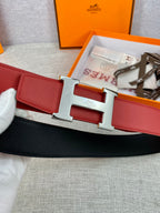 Hermes belt detail: red leather strap with silver H buckle and black backing