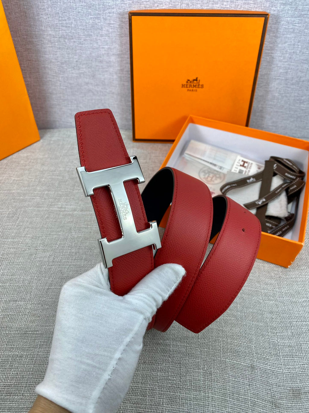 Hermes belt close-up: red leather straps with silver H buckle and black lining