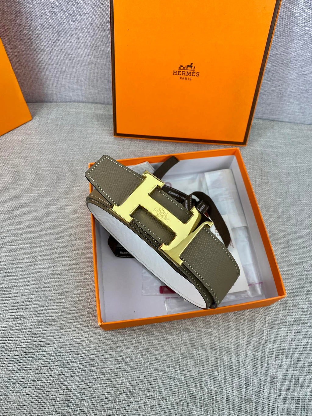 Olive leather belt with metal buckle and white protective paper inside box