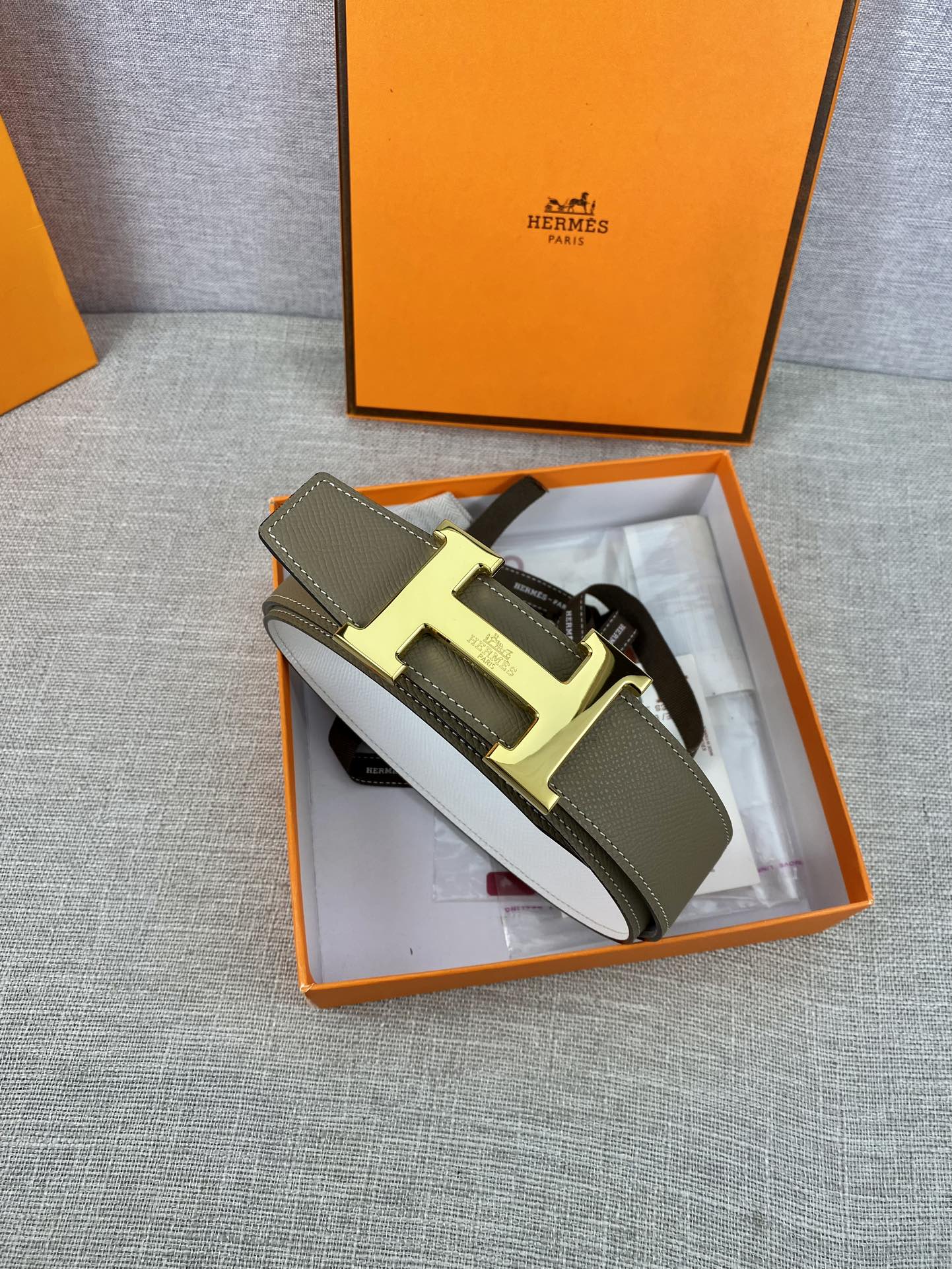 Olive leather belt with metal buckle and white protective paper inside box