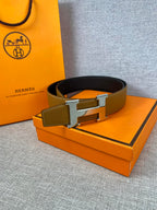 Hermes belt resting on box: tan strap with gold buckle and dark underside