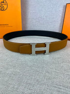Hermes belt with tan strap, gold H buckle, and dark underside