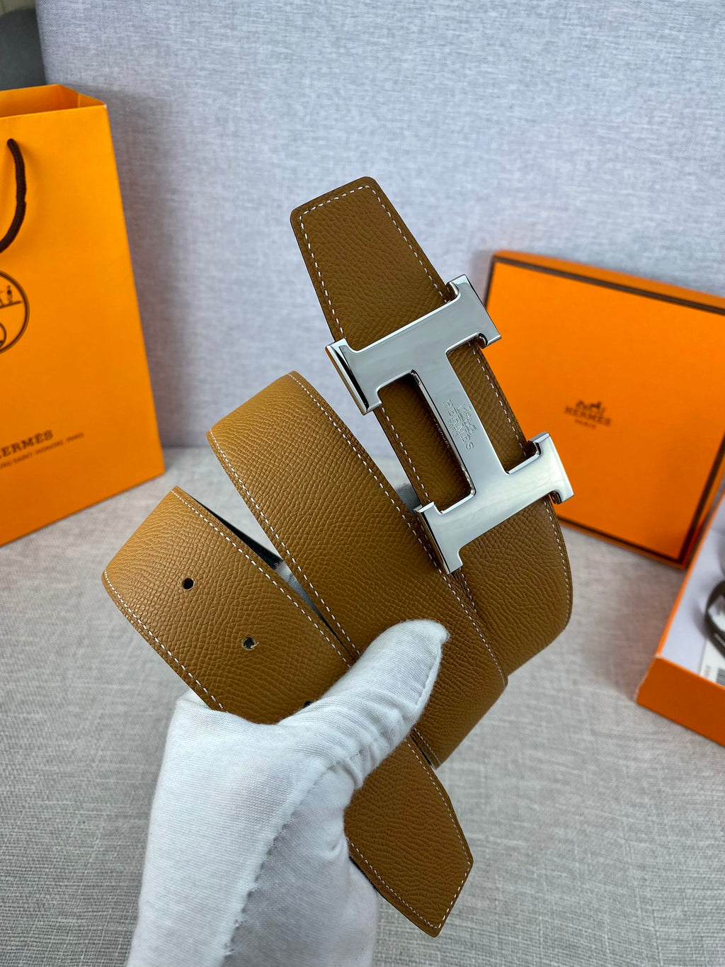 Hermes belt with tan leather strap, gold buckle, and adjustment holes
