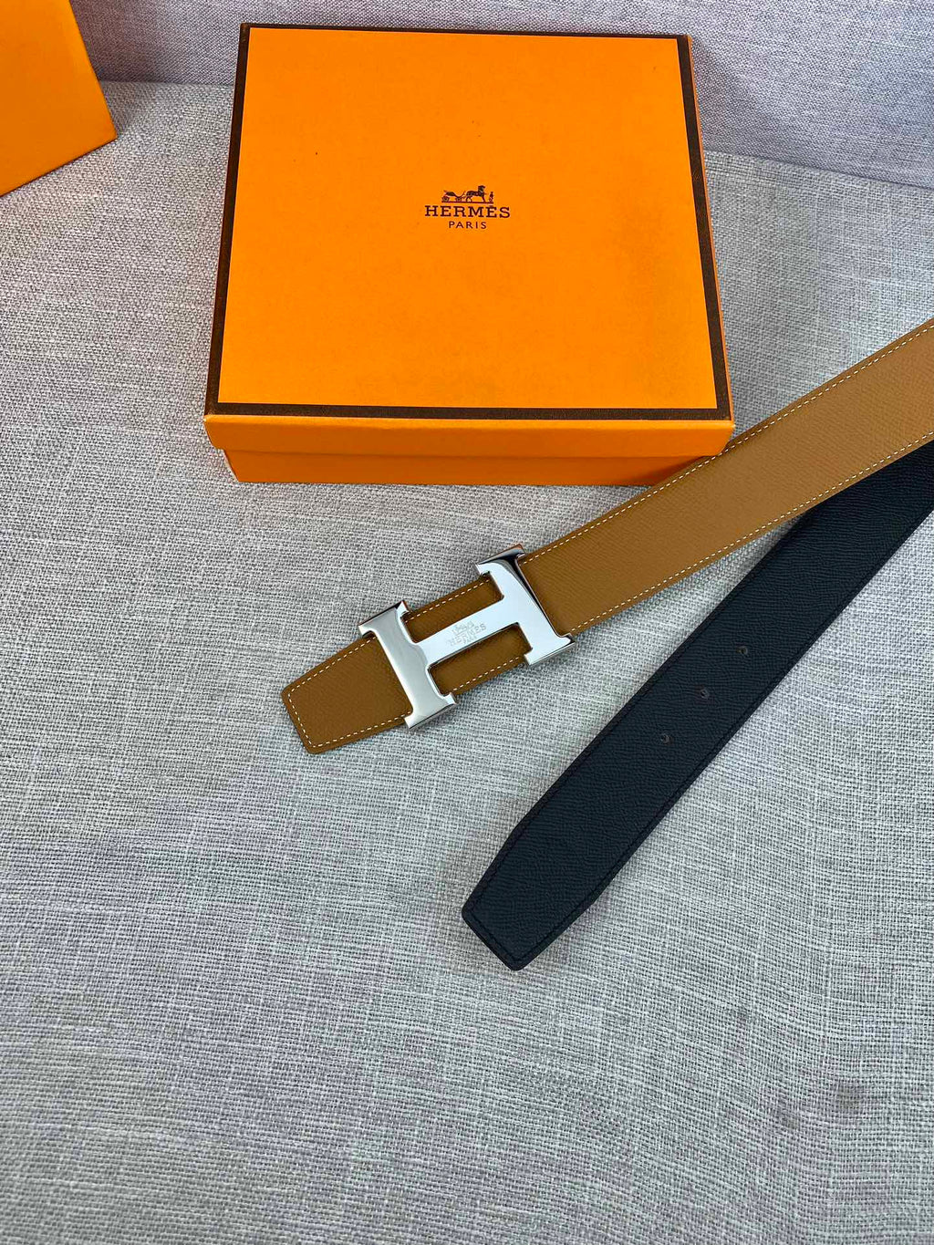 Hermes belt with tan strap and gold buckle, navy strap end on box