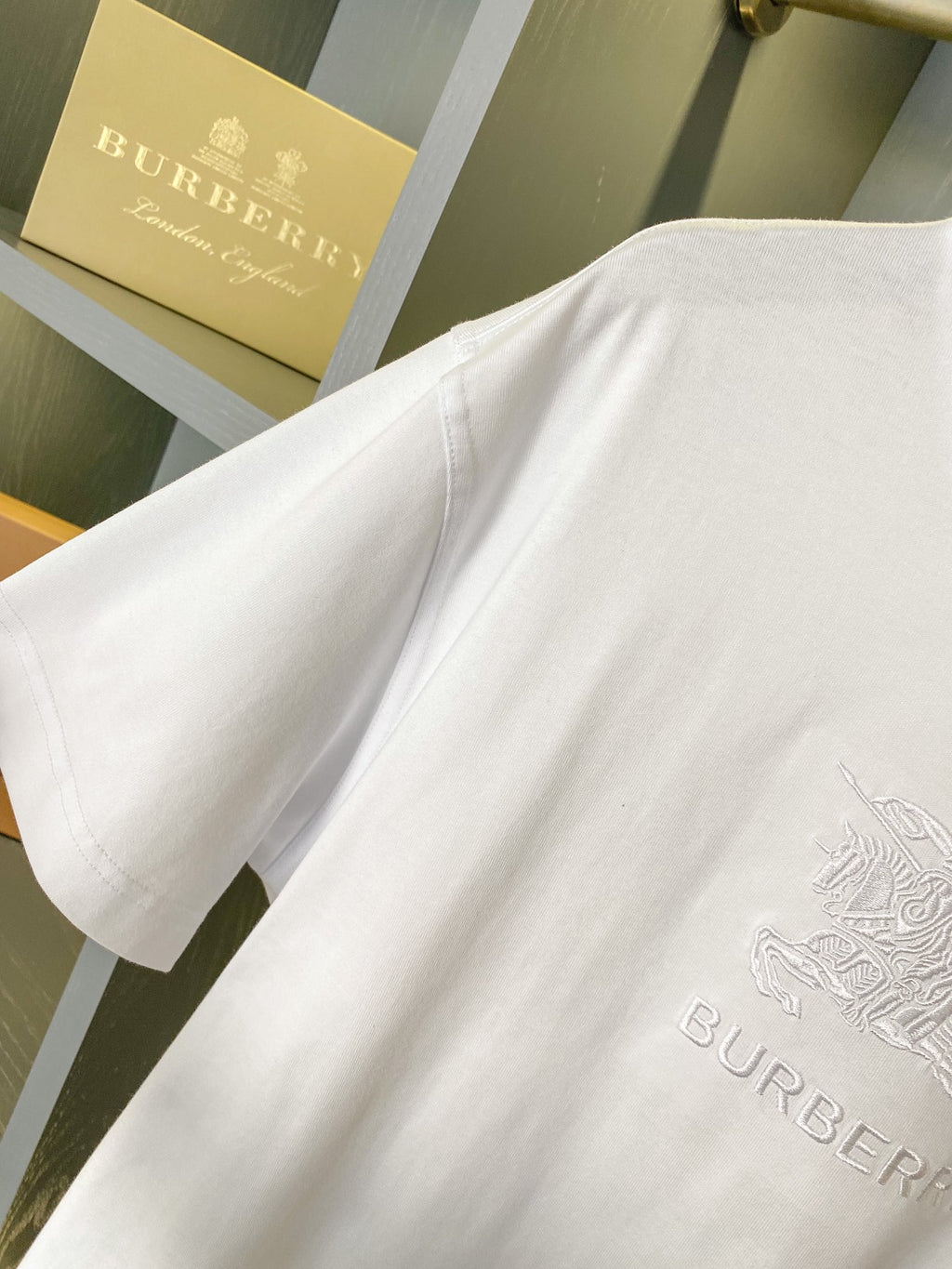 White T-shirt fabric close-up with embossed logo graphic near the lower front