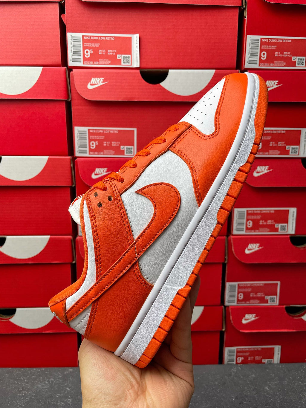 Side view of orange and white low-top sneakers with swoosh and orange lace-up