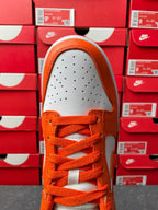 Front view of orange and white low-top sneakers with perforated toe box and laces