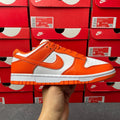 Orange and white low-top sneakers with white swoosh, orange laces, and gray sole