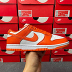 Orange and white low-top sneakers with white swoosh, orange laces, and gray sole