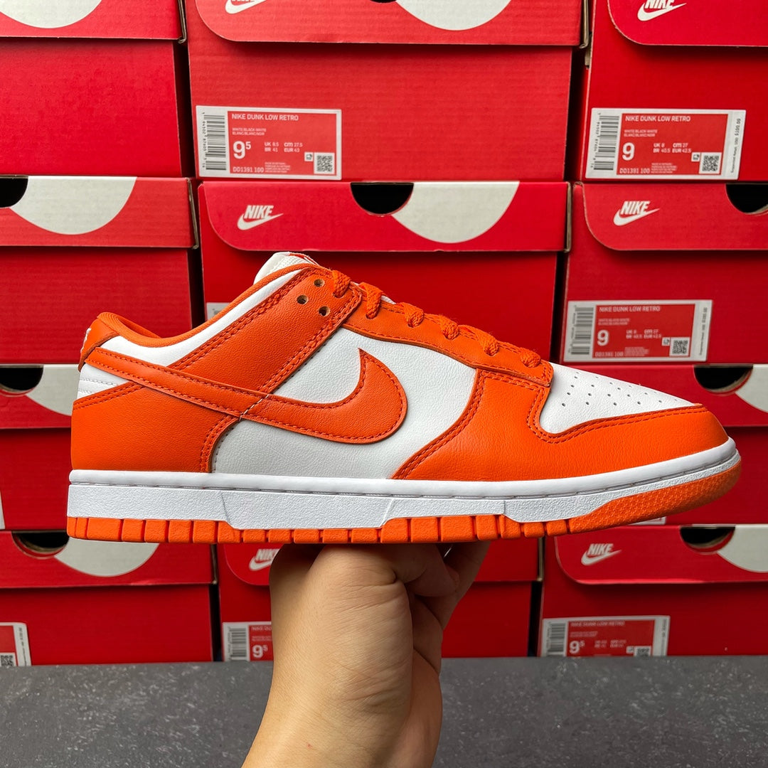 Orange and white low-top sneakers with white swoosh, orange laces, and gray sole