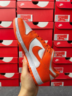 Three-quarter view of orange and white low-top sneakers with swoosh and lace-up