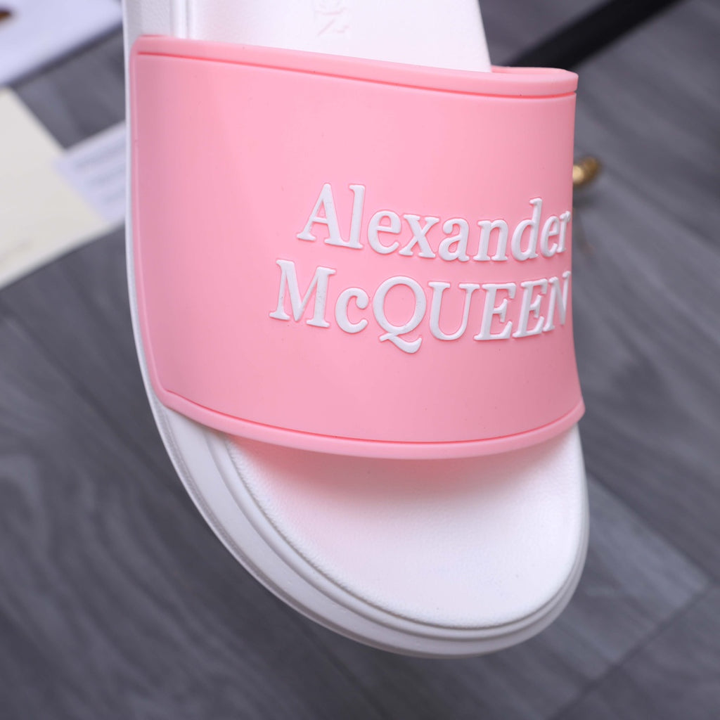 Alexander McQueen slide sandal close-up: pink logo strap on white footbed