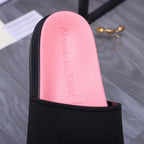 Close-up of pink insole inside a black slide sandal; embossed Alexander McQUEEN text