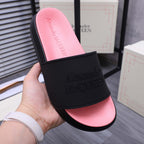 Single slide sandal held in hand; black band with embossed Alexander McQUEEN logo, pink footbed