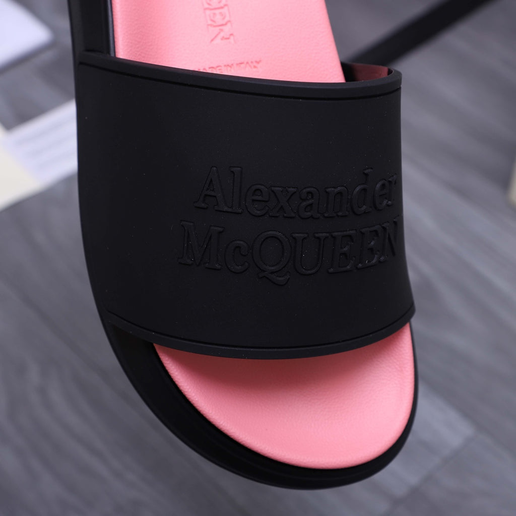 Close-up of black slide sandal band showing embossed Alexander McQUEEN lettering over pink insole