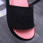 Close-up of black slide sandal band showing embossed Alexander McQUEEN lettering over pink insole