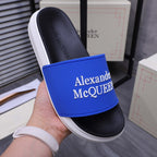Alexander McQueen slide sandal close-up, blue strap and black footbed with logo