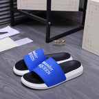 Alexander McQueen slide sandals with blue straps and white soles, angled view