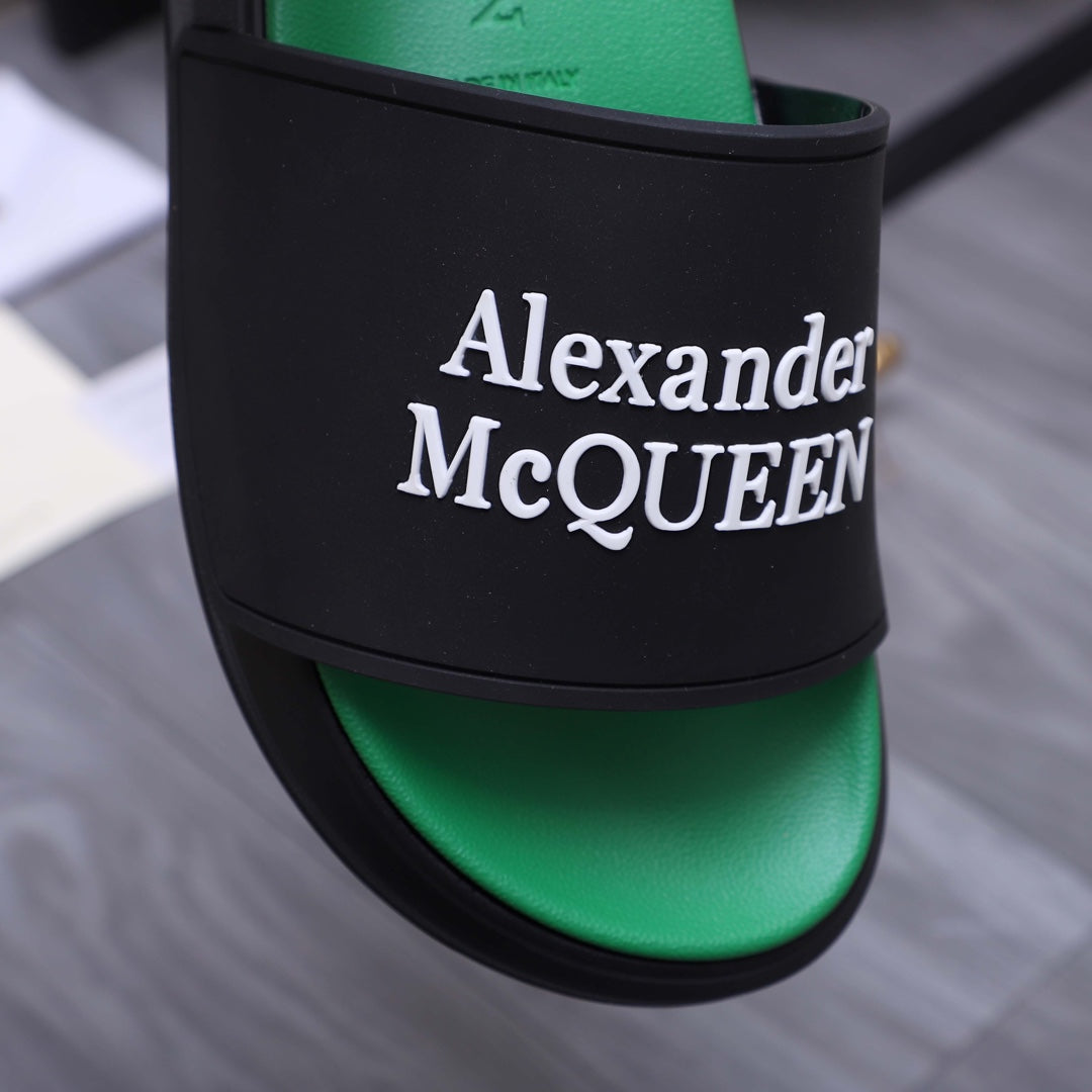 Black slide sandal band with large Alexander McQueen logo over green footbed