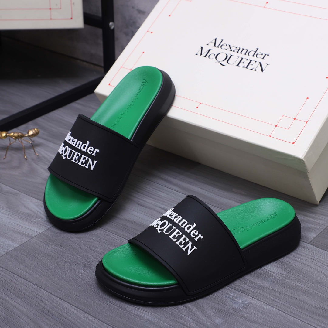Pair of green slide sandals with black straps and Alexander McQueen logos