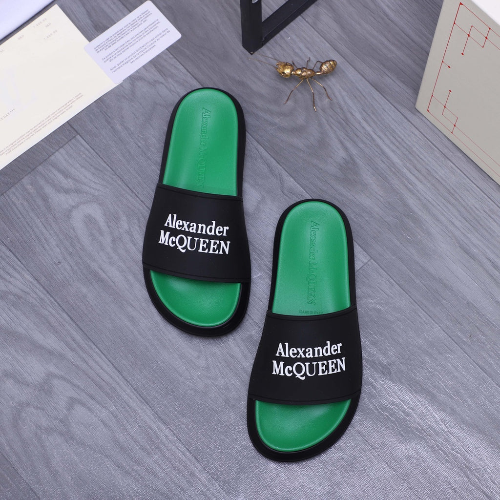 Two green slide sandals with black bands and Alexander McQueen logos