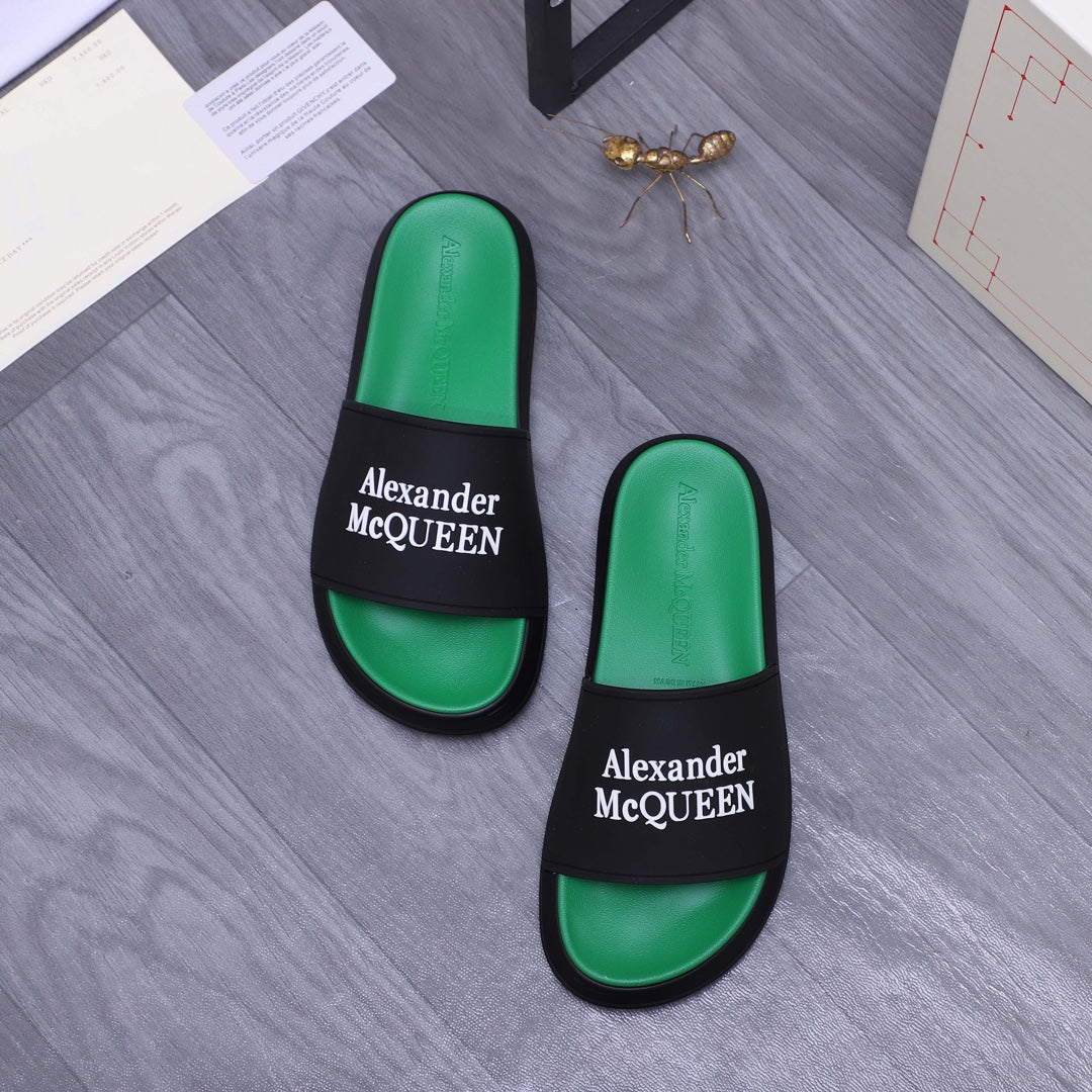 Two green slide sandals with black bands and Alexander McQueen logos