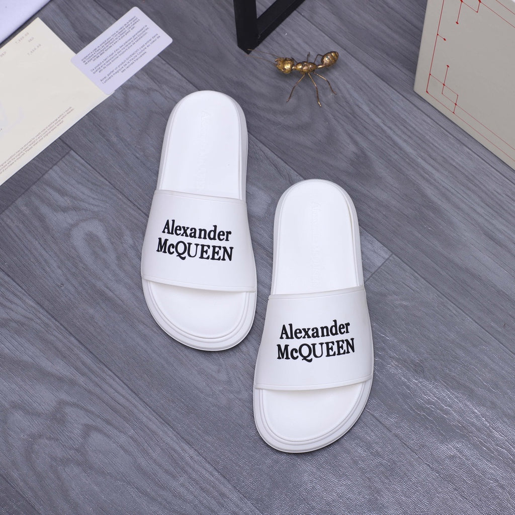 Alexander McQueen white leather slide sandals with logo straps facing camera, pair
