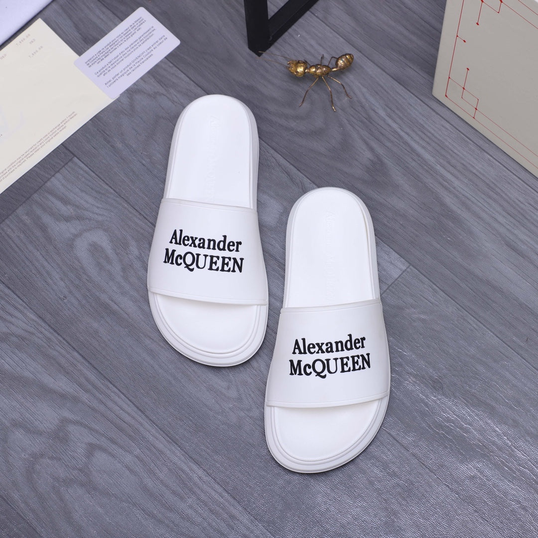 Alexander McQueen white leather slide sandals with logo straps facing camera, pair