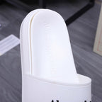 Alexander McQueen white slide sandal footbed with embossed logo, close-up