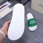 White slide sandal outsole with green logo strap, hand-held