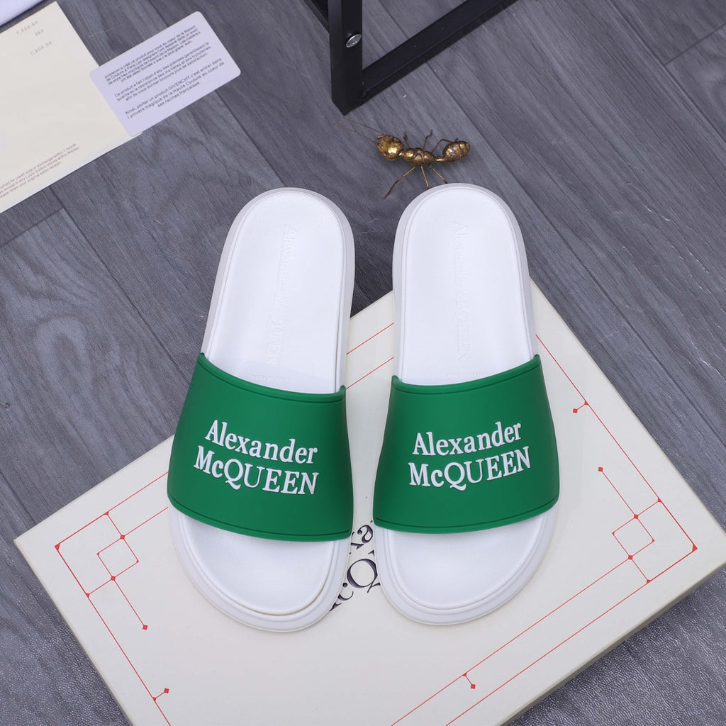 Pair of white slide sandals with green logo strap
