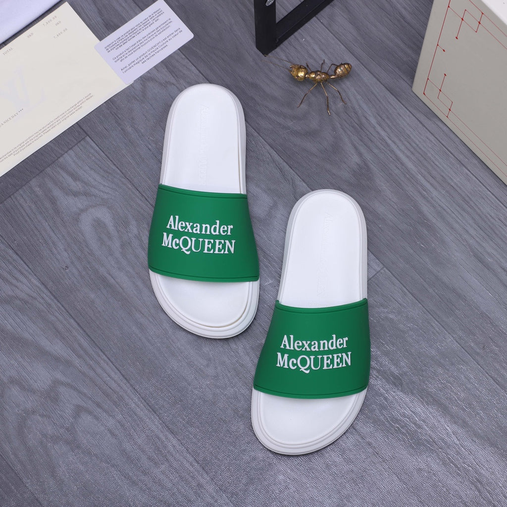 Pair of white slide sandals with green logo strap