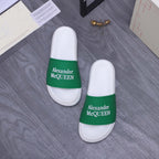 Pair of white slide sandals with green logo strap