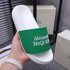 White slide sandal with green logo band, held in hand