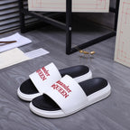 Black-and-white slide sandals with wide white strap and Alexander McQueen logo.