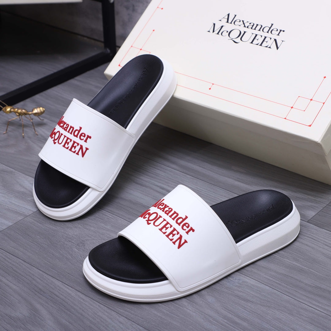 Pair of white slide sandals with black footbeds and red Alexander McQueen logo straps.
