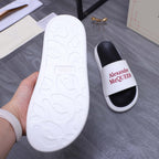White slide sandal outsole with molded pattern; other shows red Alexander McQueen logo.