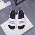 White slide sandals with black footbed and Alexander McQueen logo strap.